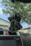 Plague Doctor Charm with a detailed mask, green ribbon, and decorative beads hanging from a car's rearview mirror.