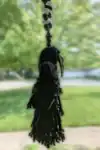 Side view of the Plague Doctor Charm with a removable mask, hanging by a string decorated with hematite and quartz beads.