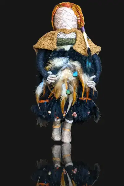Full front view of Ella the forest spirit art doll, adorned with a feathered dress and cloak, her reflection mirrored on a glassy surface like calm waters.