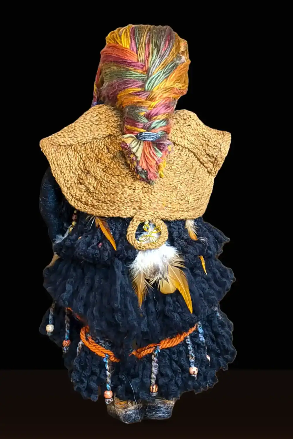 Back view of Ella the forest spirit art doll, showcasing her herringbone braid, intricate cloak with a talisman, and a layered dress adorned with feathers and beads.