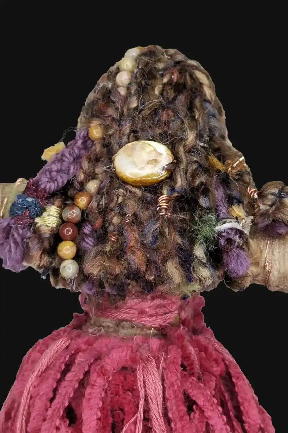 Back view of Absynthe Healing Art Doll showcasing multicolored yarn braids adorned with a shell barrette, copper coils, and earthy tones, set against a black background.