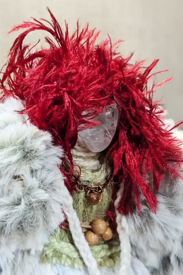 Close-up of Brigit You-Do-You Voodoo™ doll showing clear quartz crystal face, vivid red yarn hair, faux fur coat, copper chain necklace, and triple-bead belt (for the triple goddess, of course).