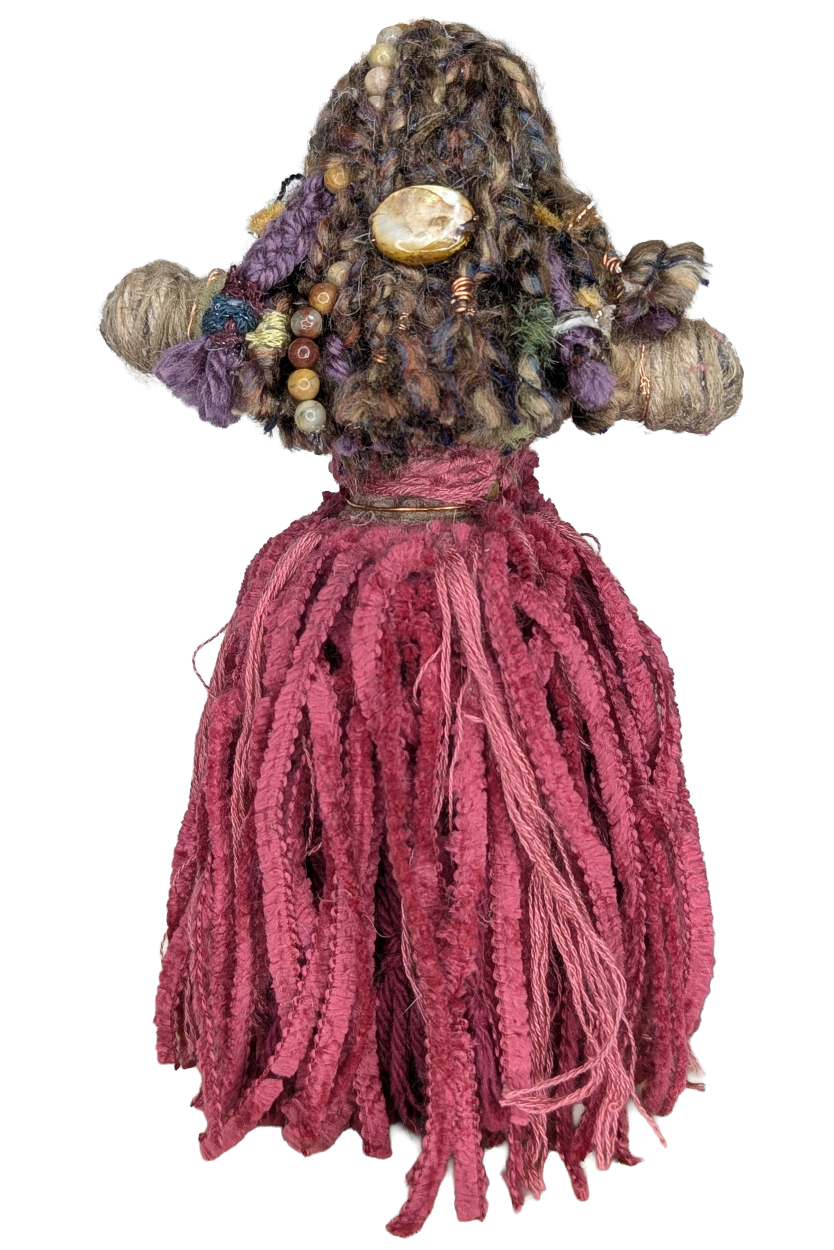 Handmade fiber art doll with braided yarn hair adorned with beads and a large stone, wearing a fringed pink yarn skirt